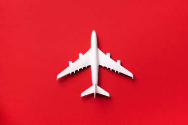 Seyahat, tatil konsepti. Kırmızı arka planda, fotokopi alanı olan beyaz model uçak. Üst Manzara. Düz yatıyordu. Asgari biçim tasarımı.