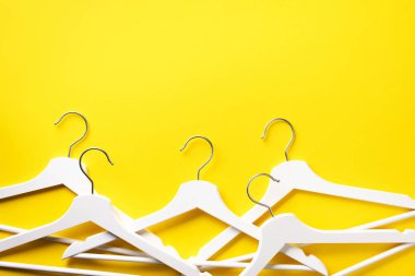 Beyaz elbiseler sarı arka planda asılı ve fotokopi alanı var. Düz yatıyordu. Üst Manzara. Minimalizm tarzı. Yaratıcı düzen. Moda, mağaza satışı, alışveriş konsepti. Kadınsı blog için afiş