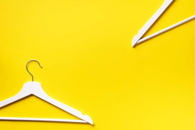 Beyaz elbiseler sarı arka planda asılı ve fotokopi alanı var. Düz yatıyordu. Üst Manzara. Minimalizm tarzı. Yaratıcı düzen. Moda, mağaza satışı, alışveriş konsepti. Kadınsı blog için afiş