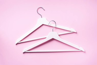 Beyaz elbise askılarının üst görüntüsü pembe arka planda ve fotokopi alanı var. Düz yatıyordu. Minimalizm tarzı. Yaratıcı düzen. Moda, mağaza satışı, alışveriş konsepti. Kadınsı blog için afiş