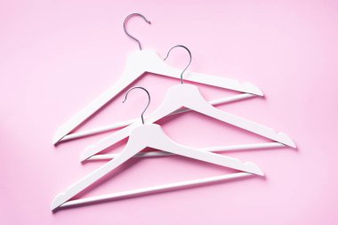 Pembe arka planda asılı beyaz elbiseler ve fotokopi alanı. Düz yatıyordu. Üst Manzara. Minimalizm tarzı. Yaratıcı düzen. Moda, mağaza satışı, alışveriş konsepti. Kadınsı blog için afiş