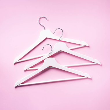 Beyaz elbise askılarının üst görüntüsü pembe arka planda ve fotokopi alanı var. Düz yatıyordu. Minimalizm tarzı. Yaratıcı düzen. Moda, mağaza satışı, alışveriş konsepti. Kadınsı blog için afiş