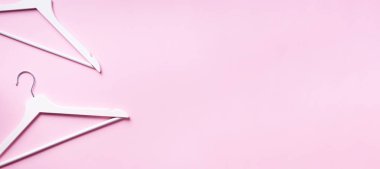 Beyaz elbise askılarının üst görüntüsü pembe arka planda ve fotokopi alanı var. Düz yatıyordu. Minimalizm tarzı. Yaratıcı düzen. Moda, mağaza satışı, alışveriş konsepti. Kadınsı blog için afiş