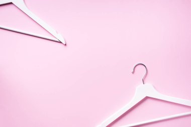 Beyaz elbise askılarının üst görüntüsü pembe arka planda ve fotokopi alanı var. Düz yatıyordu. Minimalizm tarzı. Yaratıcı düzen. Moda, mağaza satışı, alışveriş konsepti. Kadınsı blog için afiş