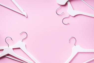 Beyaz elbise askılarının üst görüntüsü pembe arka planda ve fotokopi alanı var. Düz yatıyordu. Minimalizm tarzı. Yaratıcı düzen. Moda, mağaza satışı, alışveriş konsepti. Kadınsı blog için afiş
