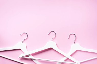 Pembe arka planda asılı beyaz elbiseler ve fotokopi alanı. Düz yatıyordu. Üst Manzara. Minimalizm tarzı. Yaratıcı düzen. Moda, mağaza satışı, alışveriş konsepti. Kadınsı blog için afiş