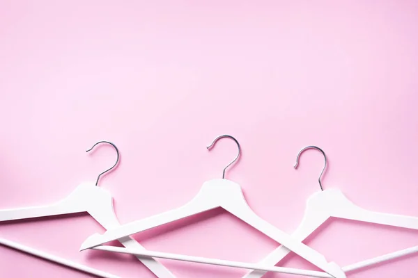Appendiabiti bianchi su sfondo rosa con spazio copia. Piatto. Vista dall'alto. Stile minimalista. Disposizione creativa. Moda, vendita di negozi, concetto di shopping. Banner per blog femminile — Foto Stock