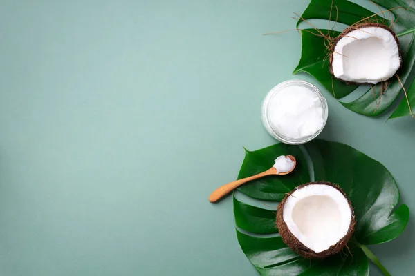Tropische Monsterblätter, reife Kokosnüsse, Kokosöl auf grünem Hintergrund mit Kopierraum. Ansicht von oben. Sommer kreative Gestaltung. Hautpflege-Kosmetik. Haare, Körperpflege — Stockfoto