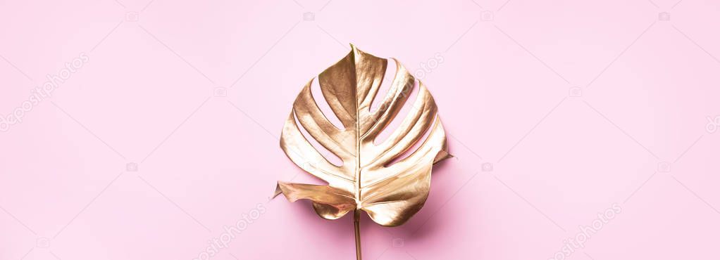 Floral minimal style concept. Exotic summer trend. Golden tropical palm monstera leaf on pastel pink color background. Shiny and sparkle design, fashion concept.