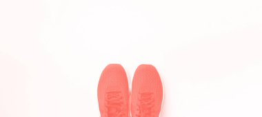 Moda mercan rengi arka planda bir çift spor ayakkabı. Üst görünüm, boşluğu kopyala. Spor, spor ve spor konsepti. Sağlıklı bir yaşam tarzı. Pankart
