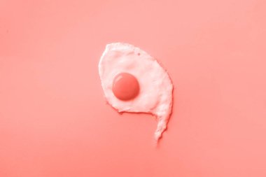 Moda mercan renginde bir sahanda yumurta. Yaratıcı gıda konsepti asgari düzeyde. Üst görünüm