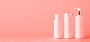 Moda mercan rengi arka planda fotokopi alanı olan beyaz kozmetik tüpleri. Cilt bakımı, vücut bakımı, güzellik konsepti. Pankart