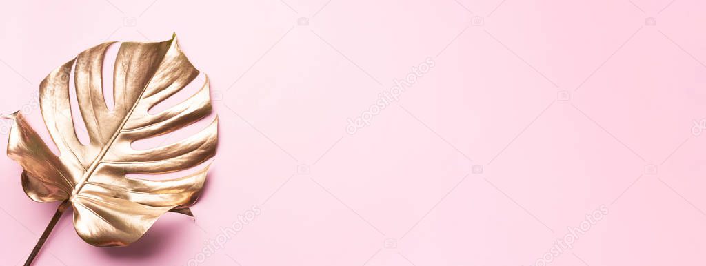 Floral minimal style concept. Exotic summer trend. Golden tropical palm monstera leaf on pastel pink color background. Shiny and sparkle design, fashion concept.
