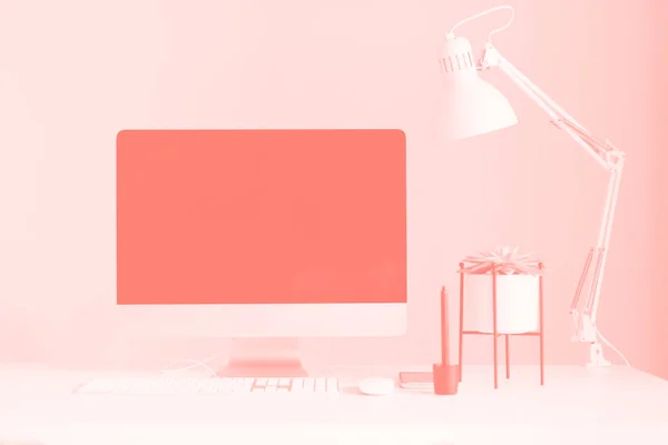 White office desk table with computer keyboard, mouse, monitor, graphic tablet, smartphone, succulent plant and other office supplies in trendy coral color. Top view, copy space, flat lay.