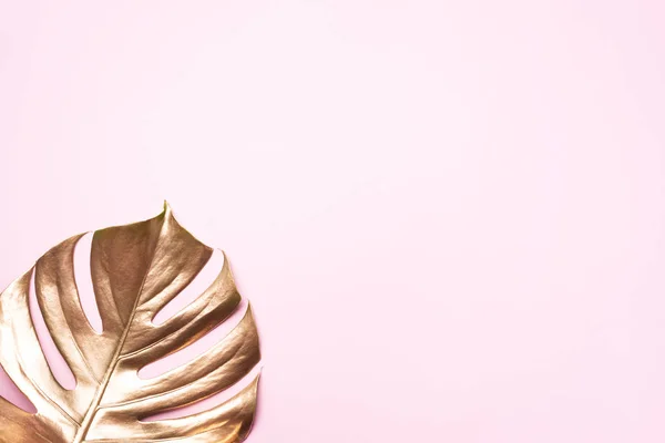 Gouden tropisch monstera blad op roze achtergrond met kopieerruimte. Bovenaanzicht. Plat gelegd. Creatieve indeling. Exotisch zomerconcept in minimale stijl — Stockfoto