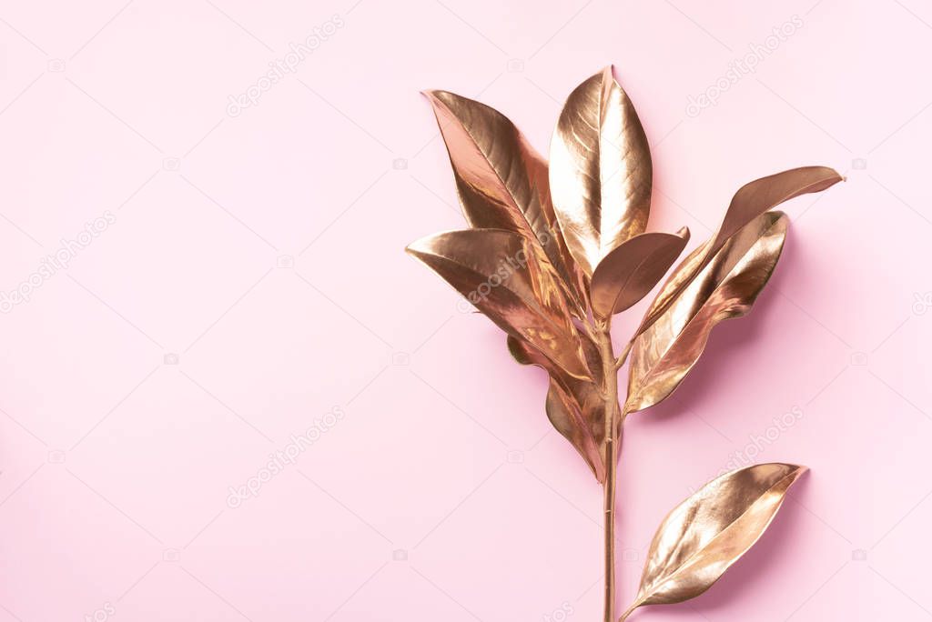 Floral minimal style concept. Exotic summer trend. Golden tropical leaves and branch on pastel pink color background. Shiny and sparkle design, fashion concept.