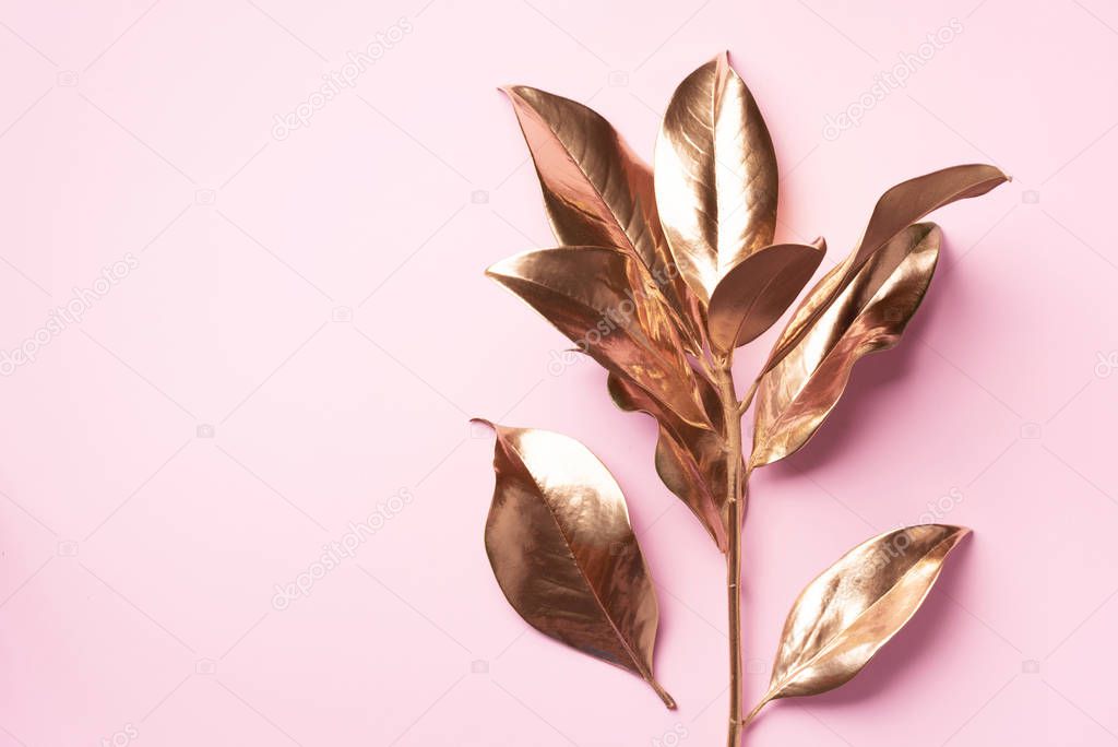 Floral minimal style concept. Exotic summer trend. Golden tropical leaves and branch on pastel pink color background. Shiny and sparkle design, fashion concept.