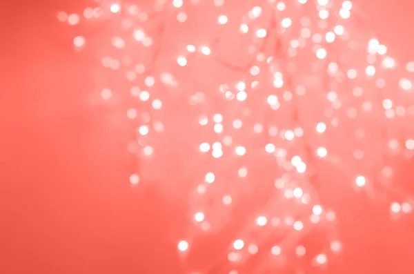 Luzes de Natal brilhantes festivas. Concreto de cimento abstrato fundo na cor de coral vivo na moda. Banner borrado com bokeh . — Fotografia de Stock