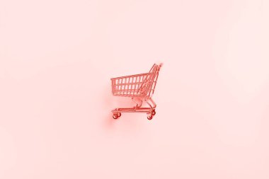 Moda mercan rengi arka planda alışveriş arabası. Minimalizm tarzı. Süpermarkette alışveriş arabası. Satış, indirim, alışveriş konsepti. Tüketici toplumu eğilimi
