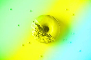 Gökkuşağı gradyan arka planında pembe kremalı tatlı çörek. Neon renkleri üzerine lezzetli donut dokusu, kopyalama alanı, üst görünüm