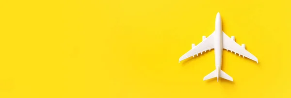 White plane, airplane on yellow color background with copy space. Top view, flat lay. Minimal style design. Travel, vacation concept. Banner.