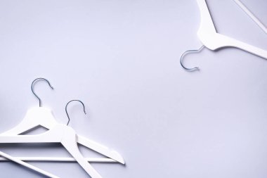 Gri arka planda, fotokopi alanı olan beyaz elbise askıları. Düz yatıyordu. Üst Manzara. Minimalizm tarzı. Yaratıcı düzen. Moda, mağaza satışı, alışveriş konsepti. Kadınsı blog için afiş