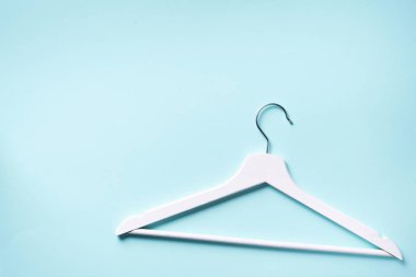 Beyaz elbise askılarının üst görüntüsü mavi arkaplanda ve fotokopi alanı var. Düz yatıyordu. Minimalizm tarzı. Yaratıcı düzen. Moda, mağaza satışı, alışveriş konsepti. Kadınsı blog için afiş