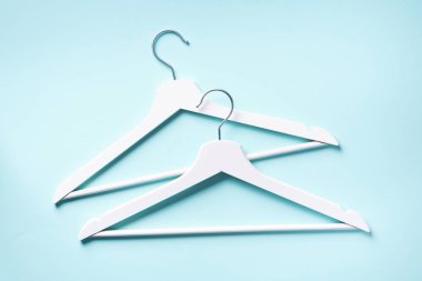 Beyaz elbise askılarının üst görüntüsü mavi arkaplanda ve fotokopi alanı var. Düz yatıyordu. Minimalizm tarzı. Yaratıcı düzen. Moda, mağaza satışı, alışveriş konsepti. Kadınsı blog için afiş