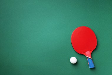 Spor, spor, sağlıklı yaşam tarzı konsepti. Masa tenisi ya da masa tenisi raketleri ve yeşil arka planda beyaz top. Üst Manzara. Düz yatıyordu.