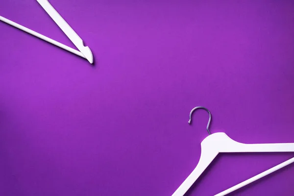 Bovenaanzicht van witte kleerhangers op violette achtergrond met kopieerruimte. Plat gelegd. Minimalistische stijl. Creatieve indeling. Mode, winkel verkoop, shopping concept. Banner voor vrouwelijk blog — Stockfoto