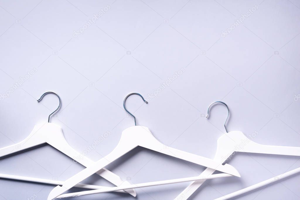 White clothes hangers on grey background with copy space. Flat lay. Top view. Minimalism style. Creative layout. Fashion, store sale, shopping concept. Banner for feminine blog