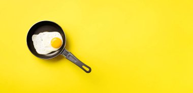 Tavada pişmiş yumurta ve sarı arka plan üzerine yaratıcı gıda konsepti. Üst Manzara. Asgari tarzda yaratıcı bir model. Düz yatıyordu.