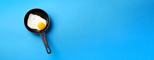 Δημιουργική ιδέα τροφίμων με τηγανητό αυγό στο τηγάνι σε μπλε φόντο. Στο πάνω μέρος. Δημιουργικό μοτίβο σε minimal στυλ. Επίπεδη. Μπάνερ — Φωτογραφία Αρχείου
