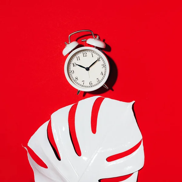 White alarm clock and monstera leaf over red background. Wake up alert concept. Morning routine. — 스톡 사진