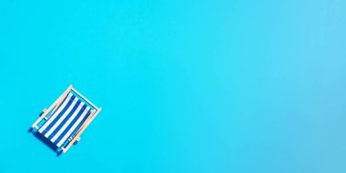 Mavi kağıt arka planda sert gölgeli güverte koltuğu. Düz yat ve uzayı kopyala. Yaz tatili konsepti. En düşük bileşim