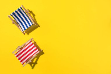 Sert gölgeli iki iskemle, sarı kağıtta canavarlar ve palmiye yaprakları. Düz yat ve uzayı kopyala. Yaz tatili konsepti. En düşük bileşim