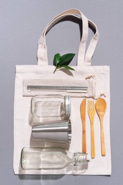 Kumaş torbaları, cam kavanozlar, metal pipetler, fotokopi alanı olan gri arka planda bambu çatal bıçaklar. Çevre dostu ve konsepti yeniden kullan. Üst Manzara. Düz yatıyordu. Sıfır atık