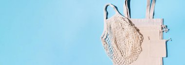Mavi arka planda örgü ve pamuk torbaları. Sürdürülebilir yaşam tarzı. Sıfır atık. Plastik yok. Pankart