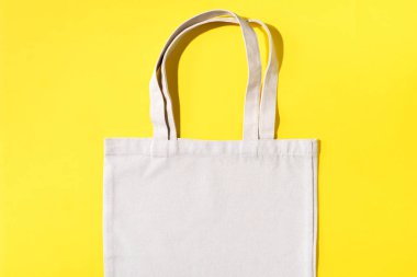 Sarı arka planda yeniden kullanılabilir tekstil torbası. Kopya alanı ile sıfır atık kavramı. Sıfır atık, plastiksiz konsept. Üst Manzara. Çevre dostu ağ tüccarı.