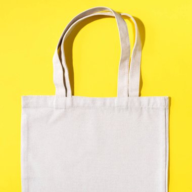 Sarı arka planda yeniden kullanılabilir tekstil torbası. Kopya alanı ile sıfır atık kavramı. Sıfır atık, plastiksiz konsept. Üst Manzara. Çevre dostu ağ tüccarı.