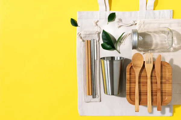 Cotton bags, glass jar, bottle, metal cup, straws for drinking, bamboo cutlery and boxes on yellow background. Sustainable lifestyle. Zero waste, plastic free shopping concept — Stock Photo, Image