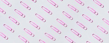 Gri arkaplanda çok renkli ataçların deseni. Okula dönelim. Ofis, iş, evrak işleri, eğitim kavramı. Pankart