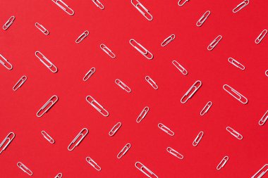 Pastel kırmızı arka planda beyaz ataçlar. Üst manzara, düz yatış. Okul konseptine geri dönelim. Üniversite, enstitü eğitimi, ofis işi