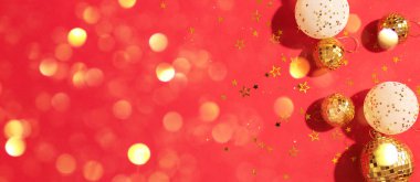 Noel kompozisyonu. Düz yerde, üst tarafta. Disko topu takısı, yıldız pırıltısı. Asgari yeni yıl partisi konsepti. Kırmızı arkaplanda fotokopi alanı olan beyaz ve altın Noel süslemeleri.