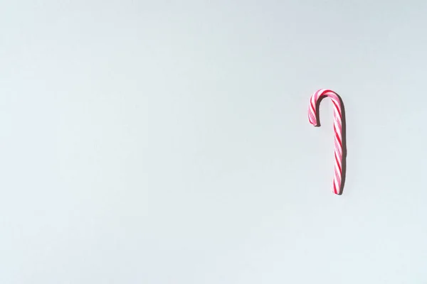 Bastón de caramelo de Navidad sobre fondo gris con espacio para copiar. Vista superior. Tarjeta de felicitación en Navidad y Año Nuevo. Concepto festivo mínimo — Foto de Stock