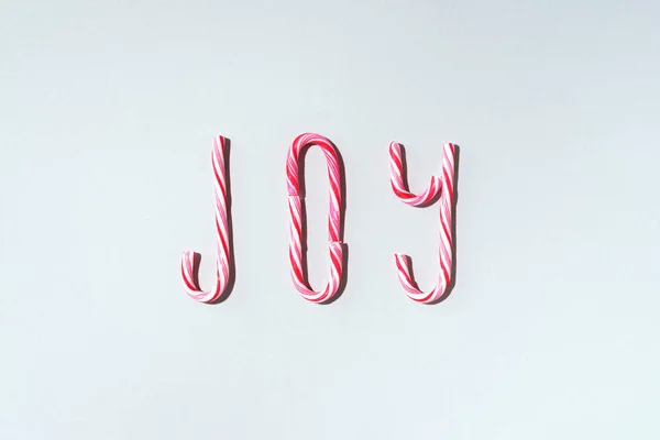 Joy word written with Christmas candy canes on grey background. Top view. Flat lay. New year and Christmas concept — Stock Photo, Image
