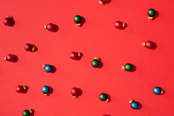 Χριστουγεννιάτικο μοτίβο από πολύχρωμα χριστουγεννιάτικα μπιχλιμπίδια σε κόκκινο φόντο. Επίπεδη θέα. Έννοια νέου έτους — Φωτογραφία Αρχείου