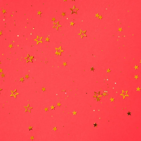 Golden star sparkles on red background. Christmas and New year concept. Festive backdrop with copy space