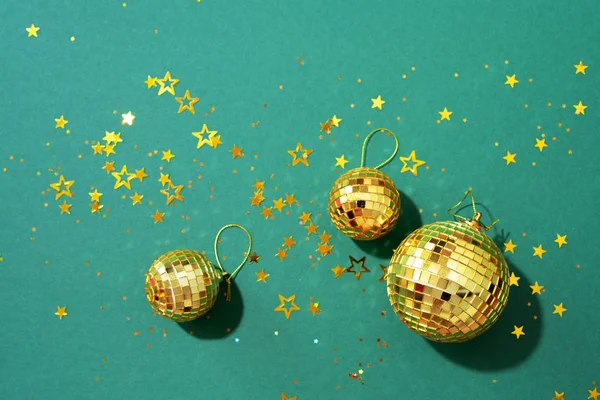 Conceito de Natal criativo. Bolas de disco de ouro brilhante sobre fundo verde. Deitado plano, vista superior. Bugigangas de Ano Novo, brilhos de estrela. Hora da festa. Cartão de saudação — Fotografia de Stock