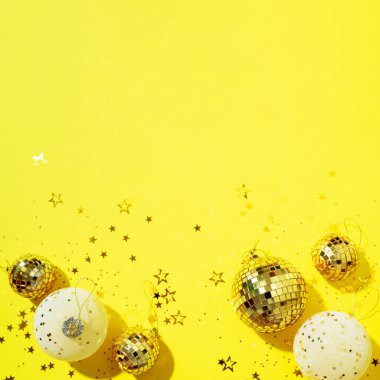 Noel beyazı ve altın süslemeler, ayna disko topları, sarı arka planda yıldız parıltısı. Düz yerde, üst tarafta. Asgari yeni yıl partisi konsepti. Kopya alanı olan Noel tebrik kartı